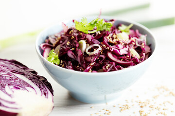 red cabbage salad, coleslaw, in a bowl on white wooden table.