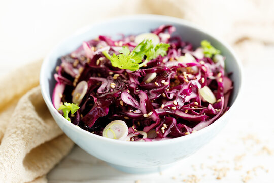 red cabbage salad, coleslaw, in a bowl on white wooden table.