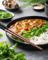 Japanese curry with rice in a black ceramic plate, selective focus, close-up