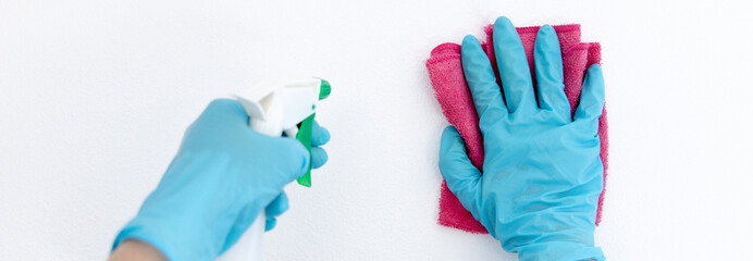 Employee's hands were wiping the white walls, use a towel moistened with cleaning solution to rub the wall, Text fill area, White background, Eliminate germs during the virus outbreak.