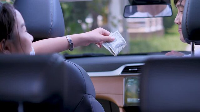 Young woman passenger giving money to taxi driver, paid for transport service. 4K