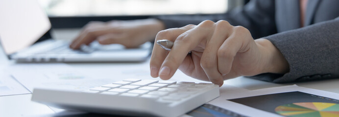 Financial or accounting professionals use a laptop to analyze the company's revenue-expenses graph to prepare for presentation to the chief executive and partner, businesswomen working.