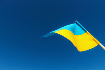 Large bicolor yellow blue Ukrainian state flag, national symbol fluttering, waving in wind against blue sky on sunny day. Kyiv city, capital of Ukraine, Independence Constitution Day, National holiday
