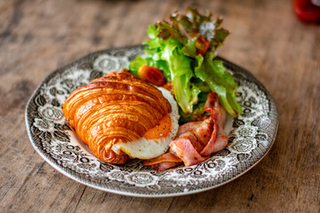 Croissant sandwich breakfast with scrambled egg, crispy bacon.