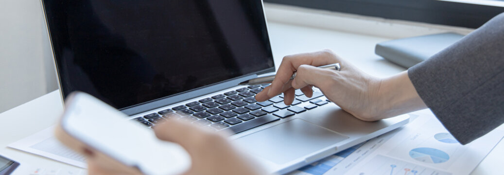 Finance workers are reviewing the company's financial data on a laptop and using smartphones to communicate or chat with the team at social distances, Working during the virus outbreak.