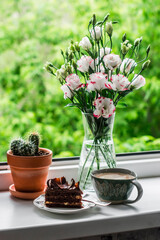 Cozy still life - a piece of chocolate cake, coffee, a bouquet of flowers on the window against the background of the garden