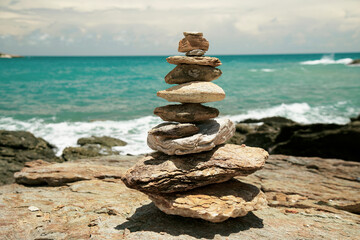 Stones balance on reef rock with a background of sea and sky, contrast sunlight in summer                                 