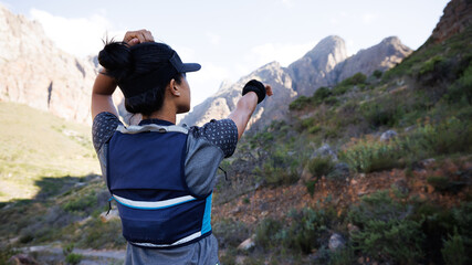 Rear view of sportswoman looking for a path and pointing to the mountain