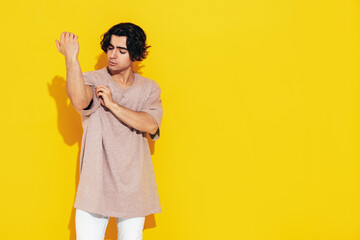 Portrait of handsome confident  stylish hipster lambersexual model.Man dressed in over size T-shirt and jeans. Fashion male isolated in studio. Posing near yellow wall