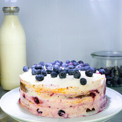 Homemade, slightly messy Victoria sponge cake with blueberries and mascarpone cream chilling in a fridge
