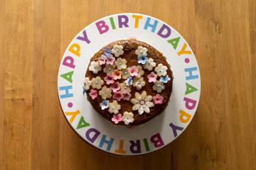 Birthday cake decorated with marzipan flowers on a decorative birthday plate