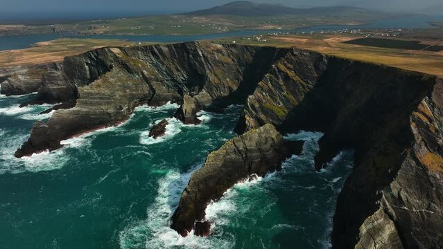 Portmagee Cliffs, Kerry, Ireland, March 2022. Drone gradually pulls southeast above the rugged coastline on the Iveragh Peninsula with Valentia Island in the distance.