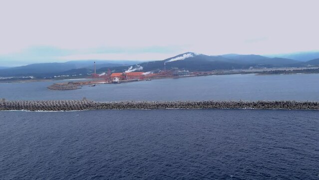 Aerial drone shot over large ship unloading raw materials in the port of the alumio factory in San Cipri&aacute;n, Mor&aacute;s, Xove, Lugo, Galicia, Spain. Aluminium factory.