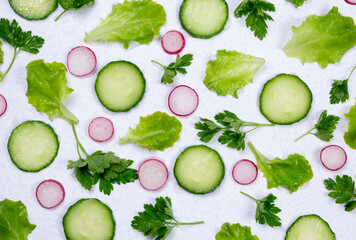 vegetable background of lettuce leaves, cucumber slices, radishes and parsley leaves on a white background. The concept of proper nutrition