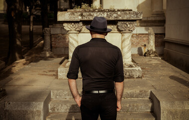 Adult man in black mourning in cemetery