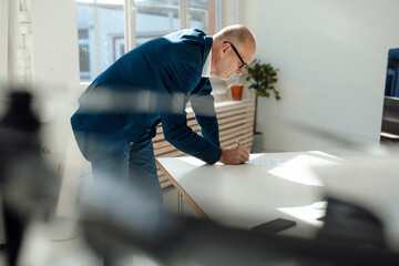 Businessman writing on document at desk in office