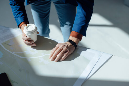 Hand of businessman wearing smart watch analyzing design at desk