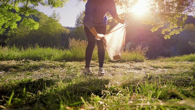 Plogging. Young woman in sports clothes jogging at the park and pick up garbage. Side view. The concept of volunteering and recycling.