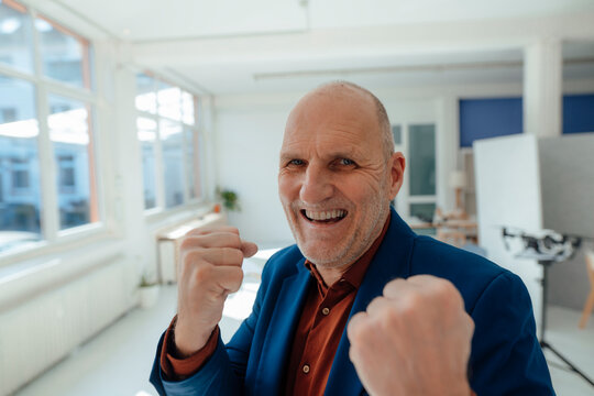 Happy businessman gesturing fists in office