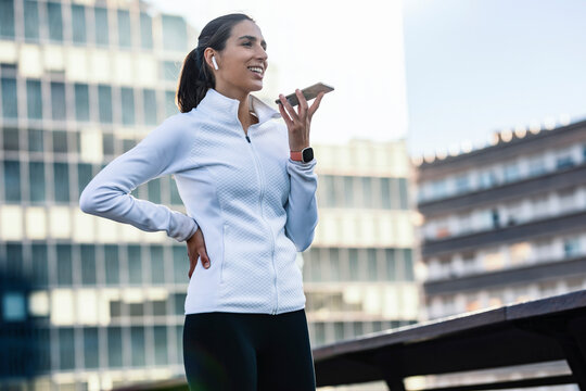 Happy Woman With Hand On Hip Talking Through Mobile Phone