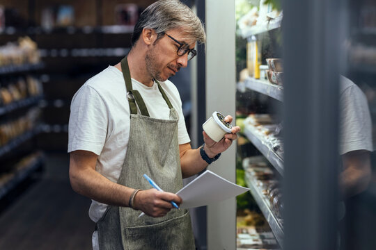 Store owner examining container working in organic market