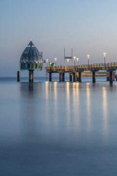 Germany, Mecklenburg-Western Pomerania, Zingst, Long exposure of Zingst Pier at dusk with Tauchgondel in background