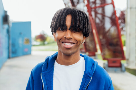 Happy young man with locs wearing dental braces