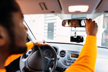 Man looking in rear-view mirror of car