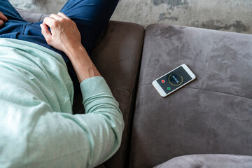 Mobile phone with timer by man sitting on sofa at home
