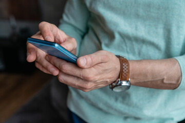Hands of man using smart phone at home