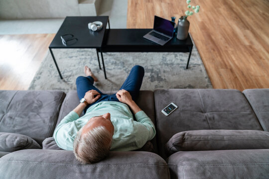 Man with timer on mobile phone relaxing in living room at home