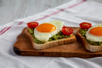 Homemade Healthy Egg, Avocado and Tomato Toast on a rustic wooden board, side view. Close-up.
