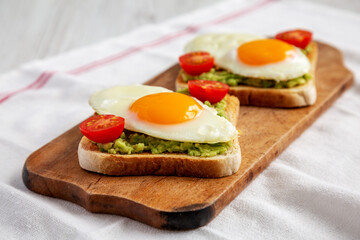 Fototapeta na wymiar Homemade Healthy Egg, Avocado and Tomato Toast on a rustic wooden board, side view.