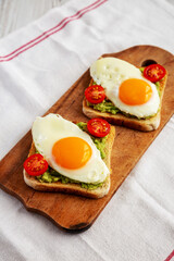 Homemade Healthy Egg, Avocado and Tomato Toast on a rustic wooden board, side view.