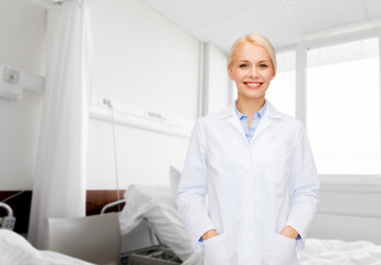 medicine, healthcare and people concept - smiling female doctor over hospital ward background