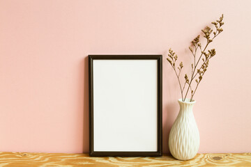 Picture frame and dry flowers on wooden table. pink wall background. copy space