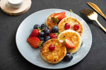 Roasted cheesecakes on a plate with powdered sugar and berries angle view