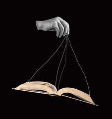 Hand holding book by strings. Using information, facts for manipulation, public influence. Propaganda, conspiracy concept. Black and white. High quality photo - obrazy, fototapety, plakaty