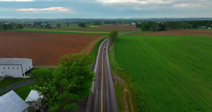 Aerial tracking shot of car on wet roads. Rural countryside after rain storm. Drone shot in American agriculture area.