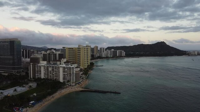 4K cinematic counterclockwise drone shot of Waikiki Beach and Diamond Head as the sun sets in Oahu. This vibrant orange Hawaiian coastal scene was filmed using a DJI Mini 2 drone.
