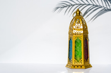 Golden lantern with shadow from sun light and leaf on white background.