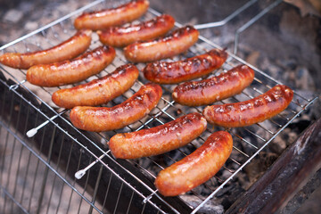 Tasty Sausages grilling on charcoal grill grate