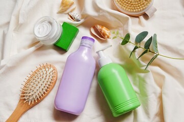 Wooden comb, purple shampoo bottle, green liquid soap package, moisturizing cream view from above flat lay photo. Natural organic cosmetic for hair and skin care