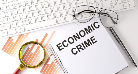 ECONOMIC CRIME text written on a notebook with keyboard, chart,and glasses