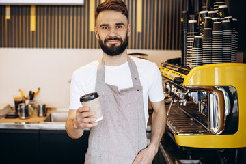 Male barista serving coffee in cardboard cups