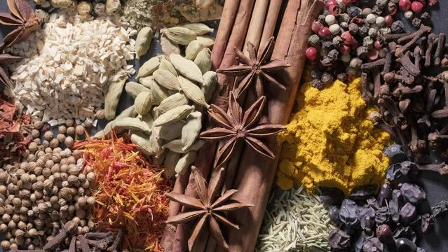 4K. Spices. Aromatic Indian spices on a slate background. Spices and herbs rotate on a stone background. Assortment of Seasonings, condiments, Dry colorful condiments. Culinary, cooking ingredients