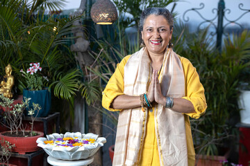 Senior indian lady standing with folded hand and welcoming .