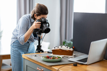 blogging, profession and people concept - female food photographer with camera photographing cake in kitchen at home