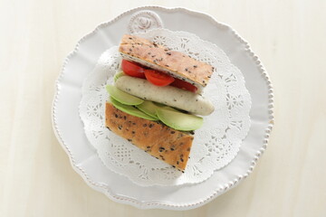 Homemade pork sausage and avocado with cherry tomato French bread sandwich