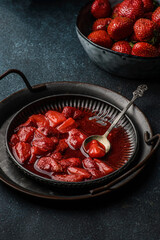 Fresh strawberry sauce on a plate on a dark background